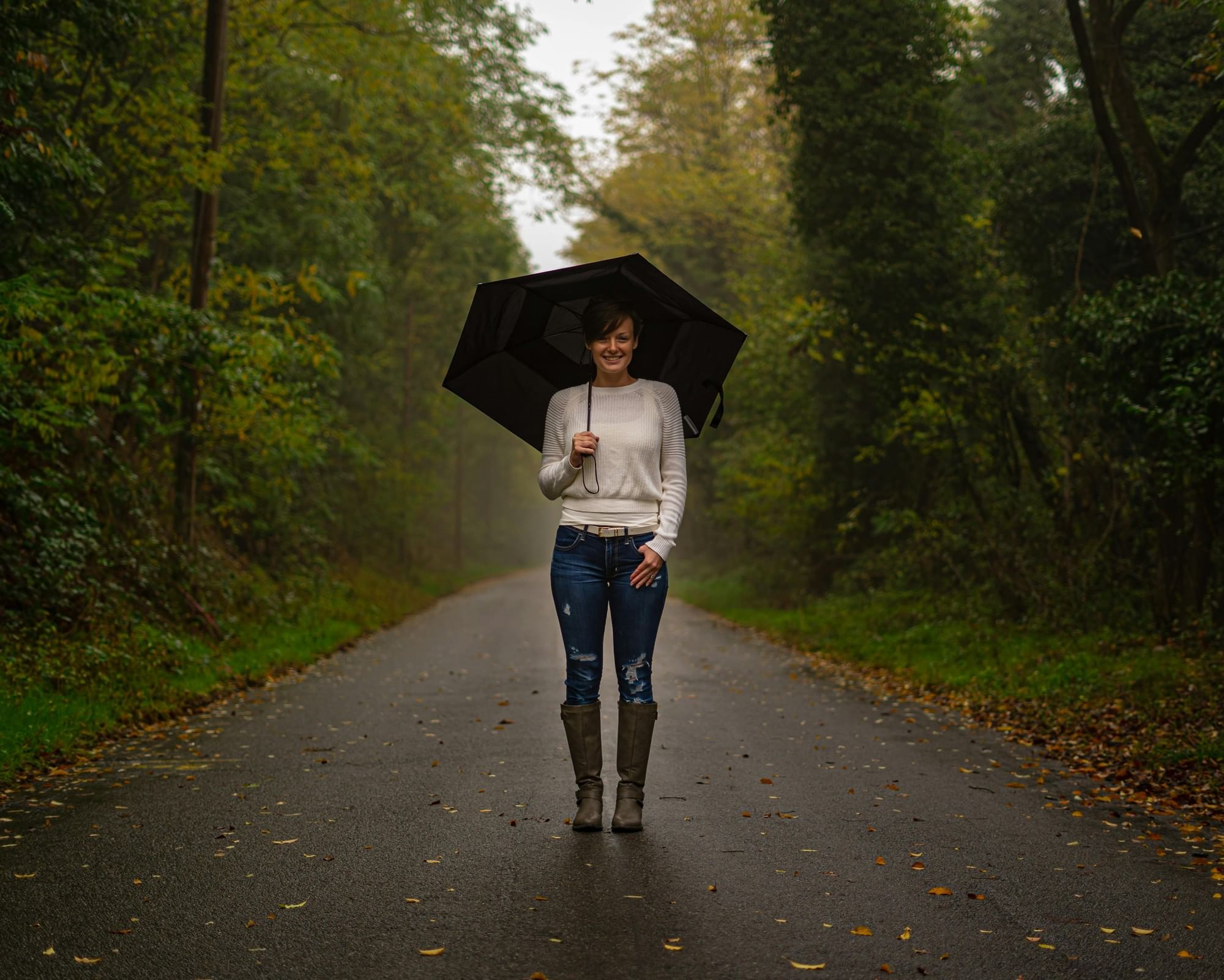 Women Standing In The Middle Of A Road Holding An Umbrella